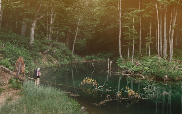 Foto excursionista de pie cerca del estanque