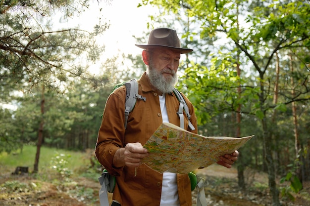 Excursionista senior mirando en un mapa de papel buscando ruta en el bosque