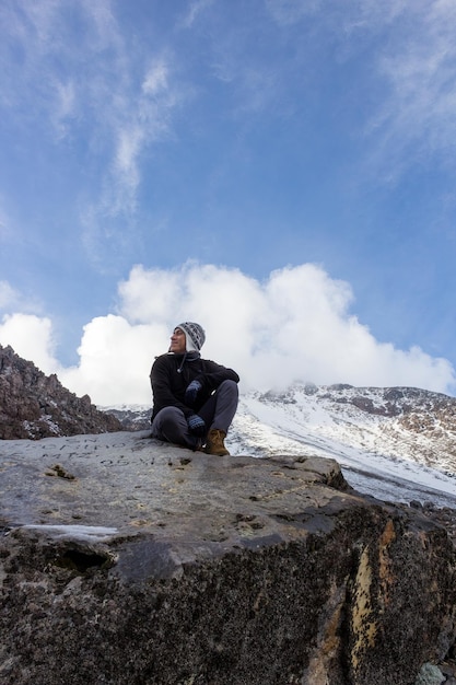 Un excursionista sentado sobre la roca en el Pico de Orizaba