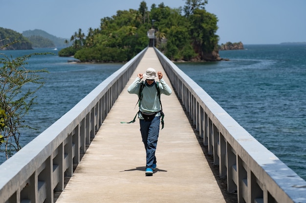 Excursionista en solitario con mochila en el puente que conduce al concepto de viaje y aventura por la isla