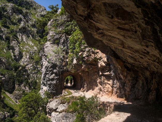 Los excursionistas atraviesan un túnel natural en las montañas.