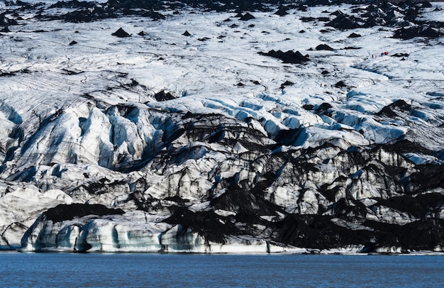 Foto excursionistas que recorren el enorme glaciar sobre el lago