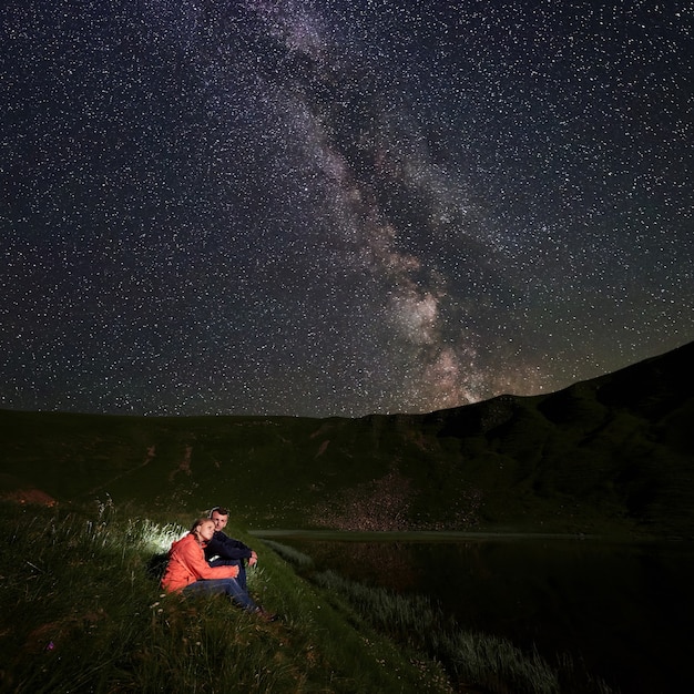 Excursionistas sentados a orillas del lago por la noche.