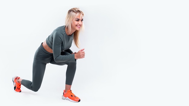 Executando uma linda garota em roupas esportivas em um fundo branco