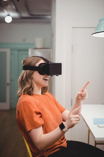 Executiva feminina usando fone de ouvido de realidade virtual no escritório