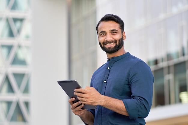 Executivo de homem de negócios indiano sorridente usando tablet digital ao ar livre