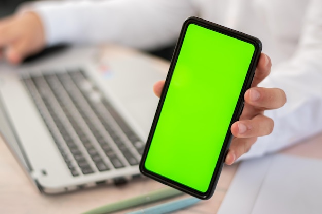 Executivo em sua mesa mostrando celular na vertical com chroma key na frente da câmera