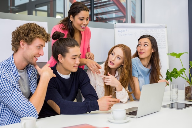 Executivos discutindo sobre laptop na sala de conferências