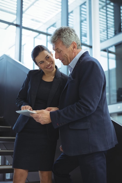 Executivos discutindo sobre tablet digital em escadas