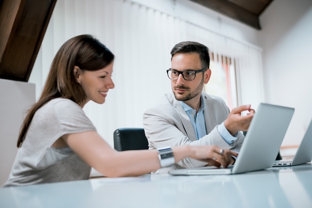 Executivos que discutem algo no portátil na mesa no escritório.