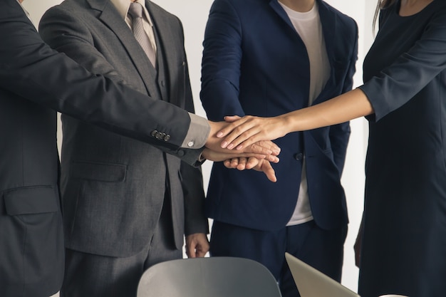 Executivos que unem as mãos, o sucesso e o conceito do trabalho da equipe.