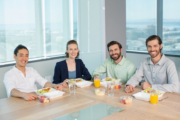 Executivos sorridentes fazendo uma refeição no escritório