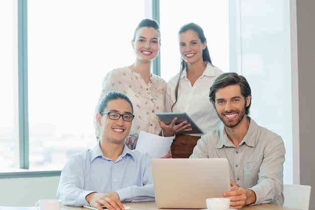 Executivos sorridentes usando laptop e tablet digital na sala de conferências