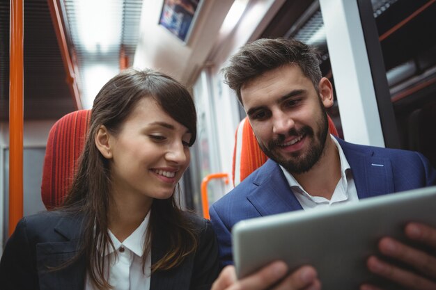 Executivos usando tablet digital viajando de trem