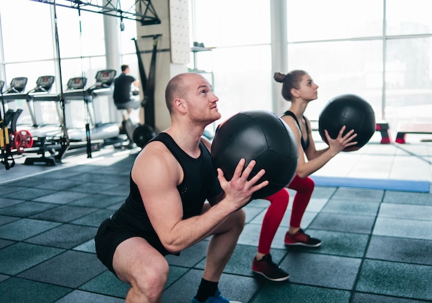 Exemplo de treinamento funcional. Desportivo homem e ajuste mulher exercitar com bola medicinal no ginásio