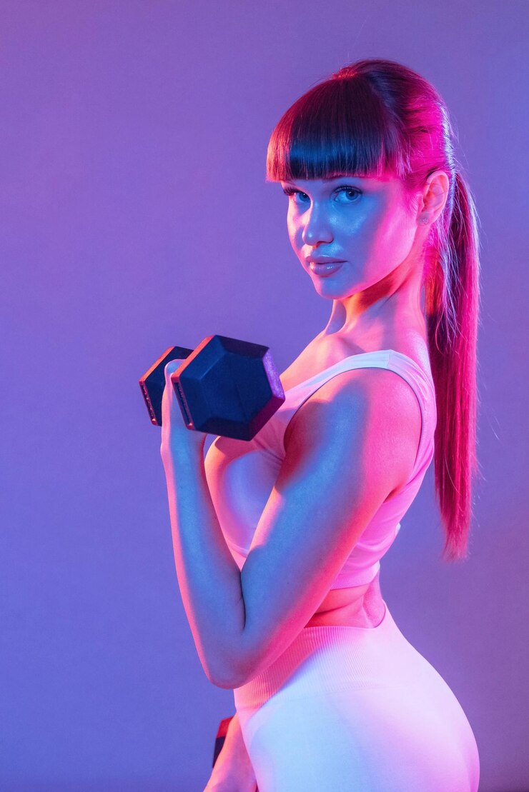 Foto exercício de braços com halteres uma jovem mulher desportiva está no estúdio
