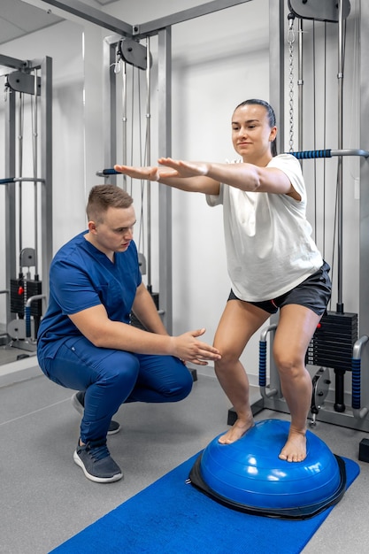 Foto exercício de equilíbrio com mulher bosu ball e médico na academia
