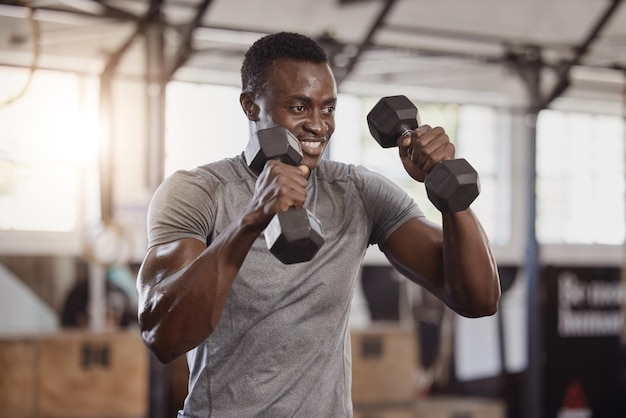 Exercício de halteres e um homem negro feliz na academia para exercícios de treinamento físico e atleta africano forte ou fisiculturista com pesos para bíceps de força e foco em um clube de bem-estar