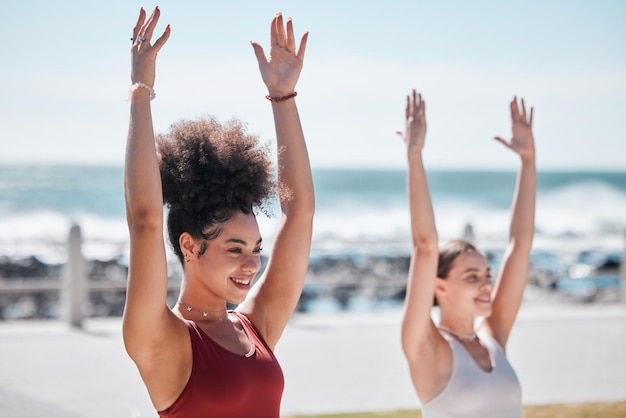 Exercício de ioga e praia com amigas ao ar livre juntas na natureza para treinamento de bem-estar Fitness chakra ou zen com uma iogue e amiga do lado de fora para um treino de saúde mental à beira-mar