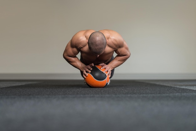 Exercício de jovem com bola médica no clube de fitness