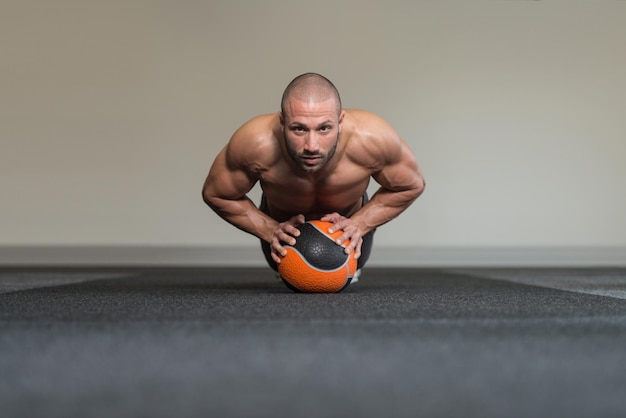 Exercício de jovem com bola médica no clube de fitness