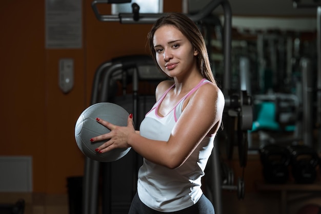 Exercício de jovem mulher com bola médica no clube de fitness