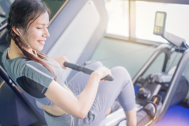 Exercício de mulher bonita de felicidade com máquina de peso de cabo no ginásio