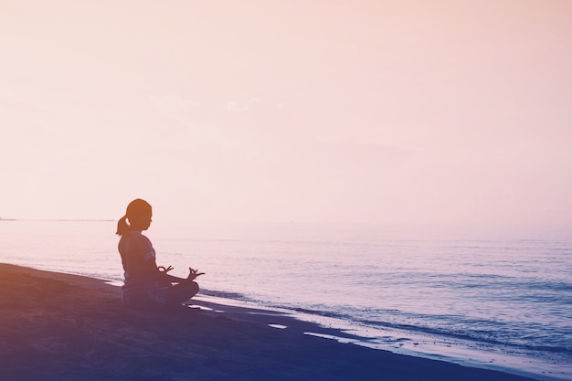 Exercício de mulher com ioga no fundo da praia com filtro vintage