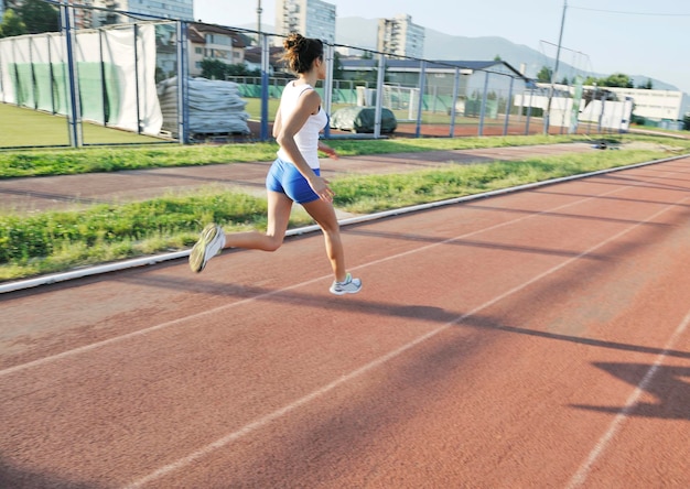 exercício de mulher jovem e bonita correndo e correndo na pista de atletismo no estádio ao nascer do sol