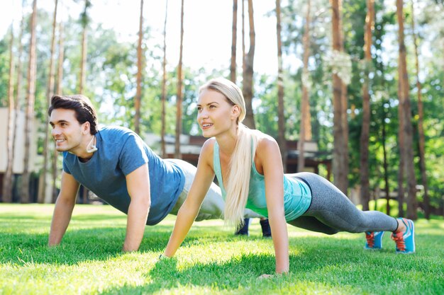 Exercício esportivo. encantadas flexões de casal agradáveis enquanto se exercitam no parque