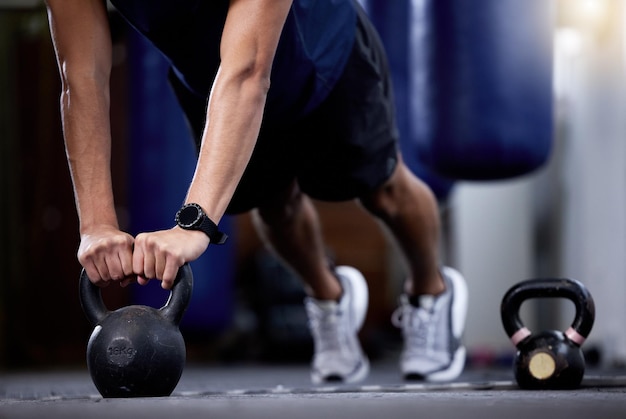 Exercício kettlebell e homem de mãos fortes fazendo exercícios de ginástica com um relógio de fitness durante o treinamento muscular como fisiculturista com pesos de metal Atleta com smartwatch para treinar para objetivos de força e saúde
