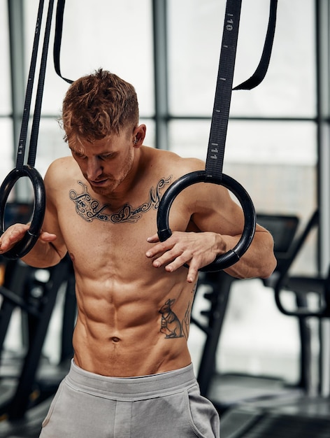 Exercício Muscleup jovem fazendo treino de cross fit intenso no ginásio em anéis de ginástica