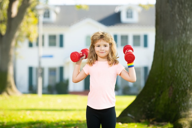 Exercícios de esportes matinais para crianças retrato esportivo crianças fitness criança com halteres no treino de ginásio de parque