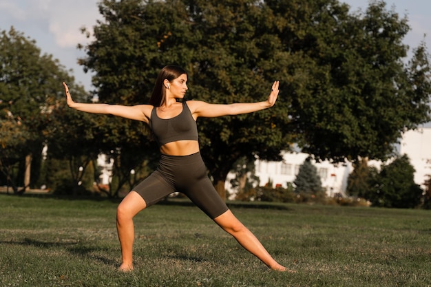 Exercícios de meditação Qigong ao ar livre Garota asiática fit faz treinamento chinês na grama verde no parque