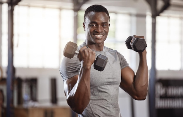 Exercite halteres e retrato de um homem negro na academia para treino de treinamento físico e atleta africano forte ou fisiculturista com pesos para potência de bíceps e desempenho em um clube