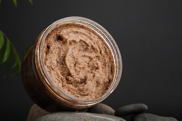 Exfoliante corporal de café y granos de café en fondo oscuro pancarta cuidado de la piel concepto de cuidado de la salud