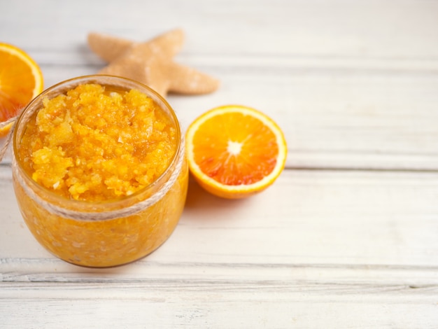 Exfoliante de naranja con sal marina en el espacio de copia de mesa de madera blanca