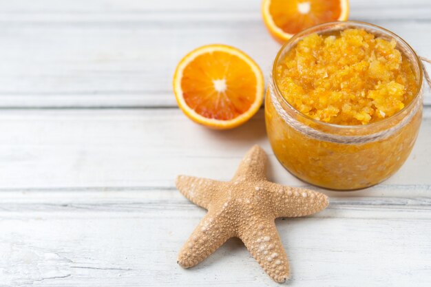 Exfoliante de naranja con sal marina en el espacio de copia de mesa de madera blanca