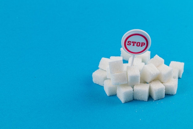 Exhibición creativa de cubos de azúcar con señal de parada contra un fondo azul