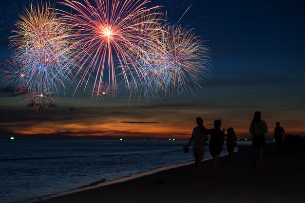 Foto exhibición de fuegos artificiales en la playa contra el cielo por la noche