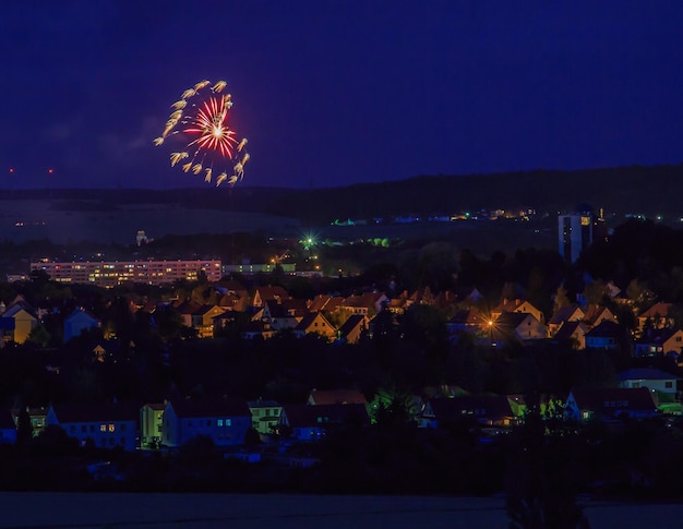 Exhibición de fuegos artificiales sobre edificios iluminados en la ciudad por la noche