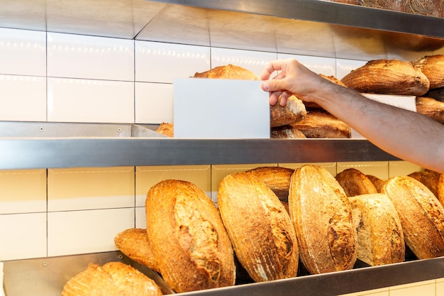 Foto exhibición de pan artesanal panes recién horneados y etiquetas organizadas por un trabajador de panadería calificado