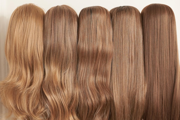 Exhibición de pelucas de aspecto natural en diferentes tonos de rubio fijadas en los soportes de la peluca en el salón de belleza