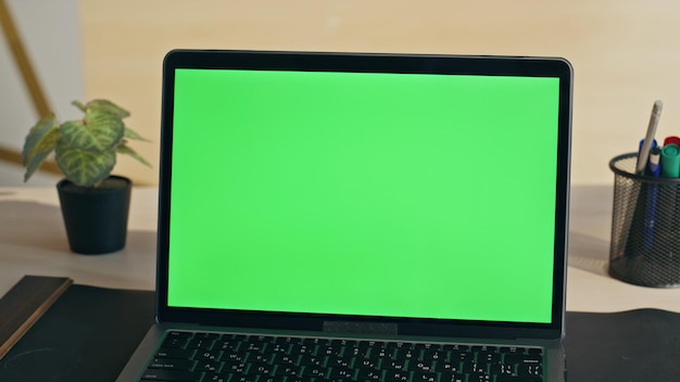 Exibição de computador portátil de chave de croma vazia em computador de tela verde de close-up no local de trabalho
