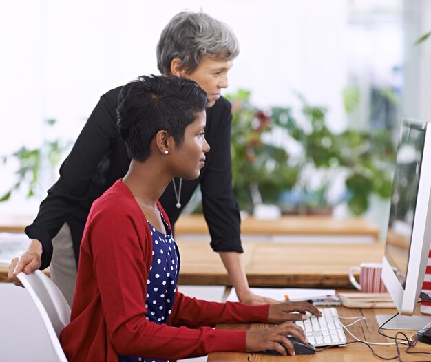 El éxito requiere trabajo duro Captura de dos colegas discutiendo el trabajo en una computadora de escritorio