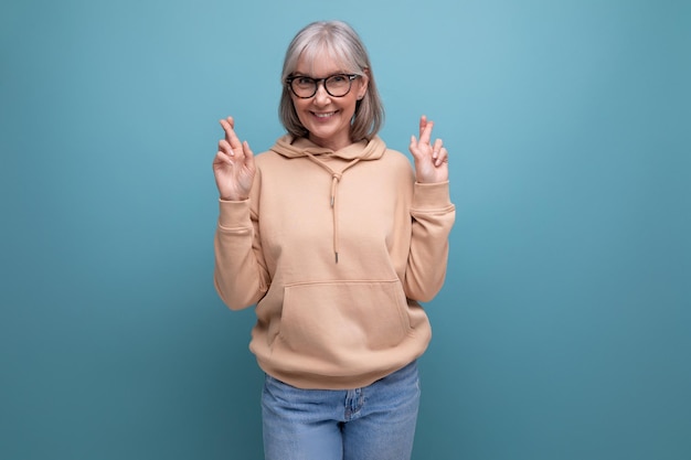 Exitosa, alegre, soñadora, mujer madura de moda vestida con ropa juvenil en el fondo del estudio con copia