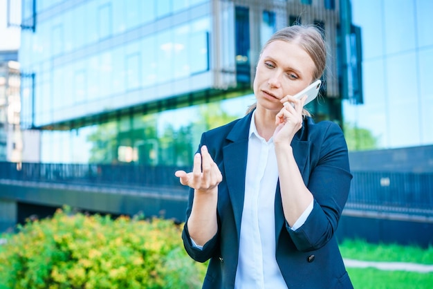 Exitosa banquera que usa un teléfono inteligente al aire libre mientras está cerca de la oficina