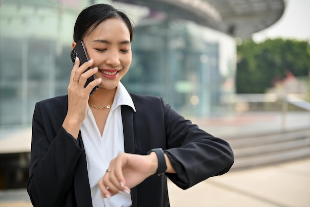 La exitosa directora ejecutiva asiática está hablando por teléfono y revisando la hora en su reloj de pulsera mientras camina