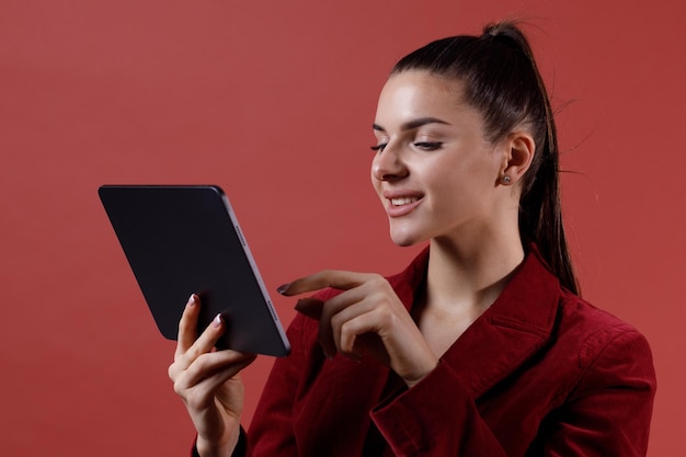 Exitosa joven empresaria moderna en viva chaqueta de traje de terciopelo magenta trabajando en tableta Concepto de mujer de trabajo de negocios