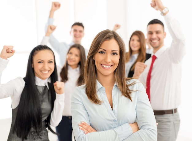 Exitosa joven empresaria parada orgullosamente con su joven equipo de negocios y mirando la cámara.